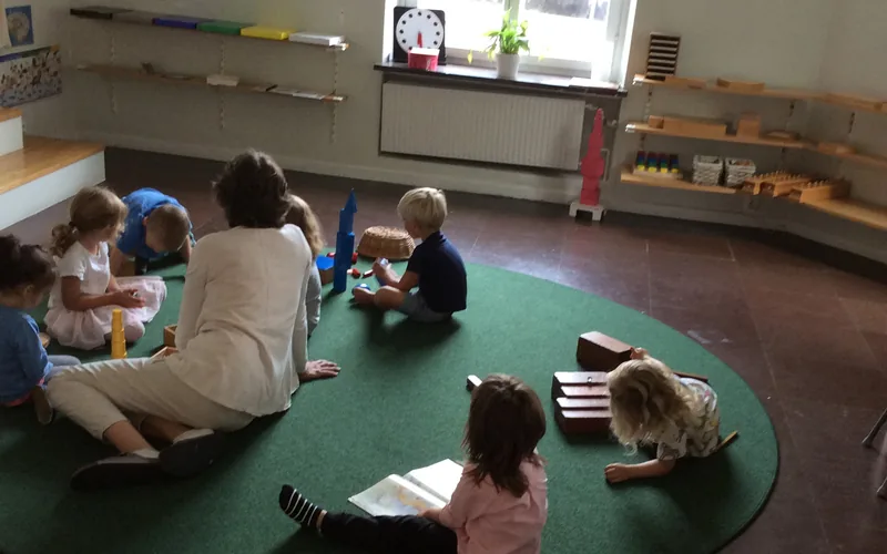 Barnen på förskolan sitter samlade på en matta tillsammans med pedagogen