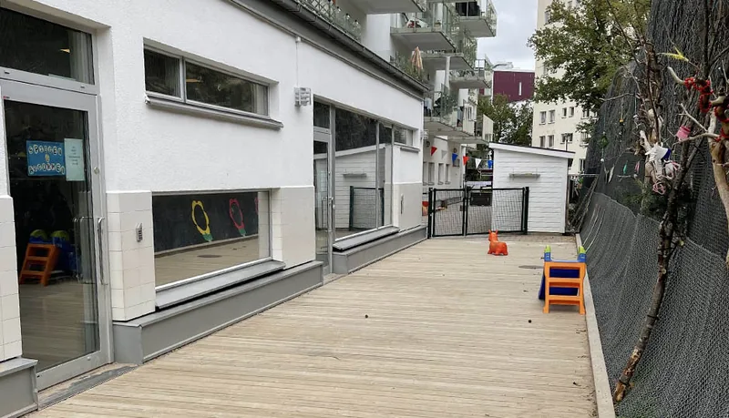 Lokal med vit fasad och trädäck utanför.