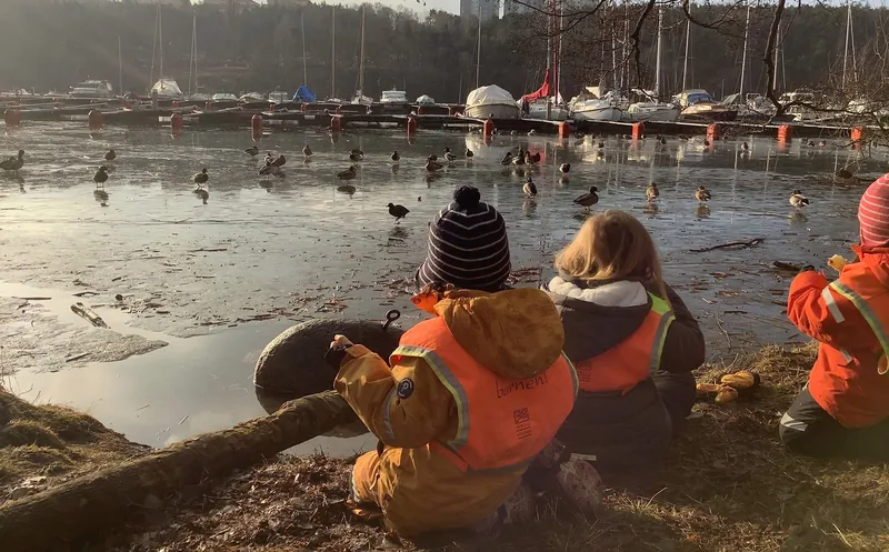 Barn sitter vid vattnet.