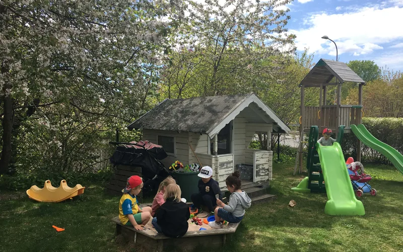 Barn, sandlåda, lekstuga, blommande träd.