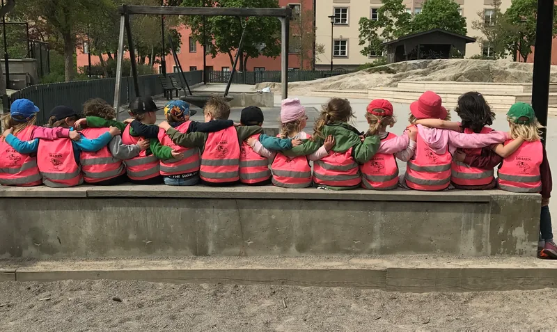 Barnen sitter i en rad och håller om varandra