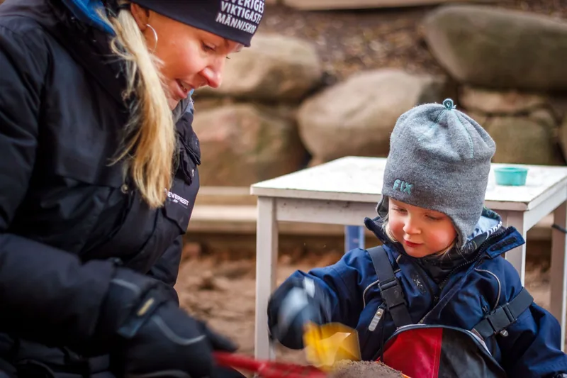 Barn och pedagog utomhus på förskolan.