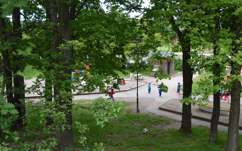 Bilden visar vår ljusa, gröna och stora innergård som erbjuder fina lekytor, lekutrustning och material för aktiva lekar.