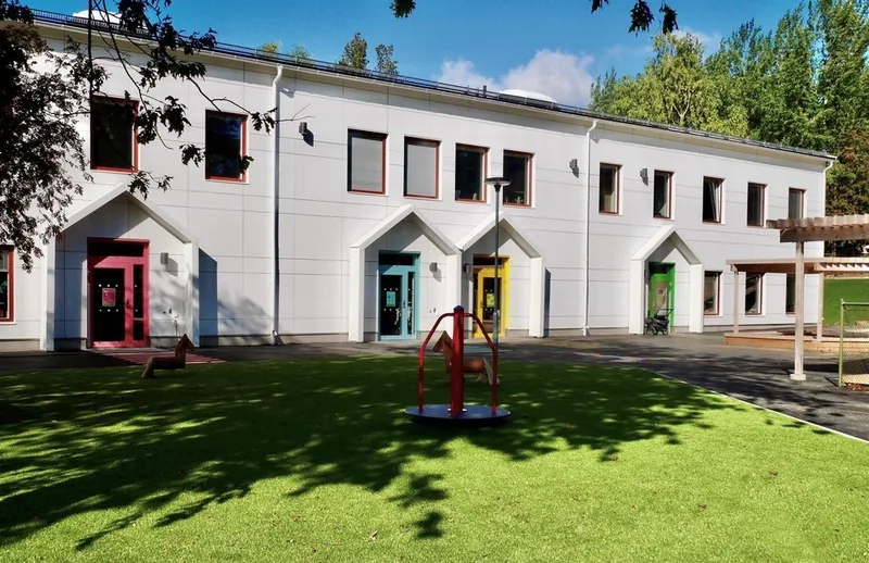 Bild på förskolan Gullängen. Ett vitt hus med färgglada dörrar.