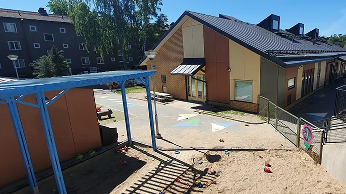 En bild på förskolan med en lekplats i förgrunden
