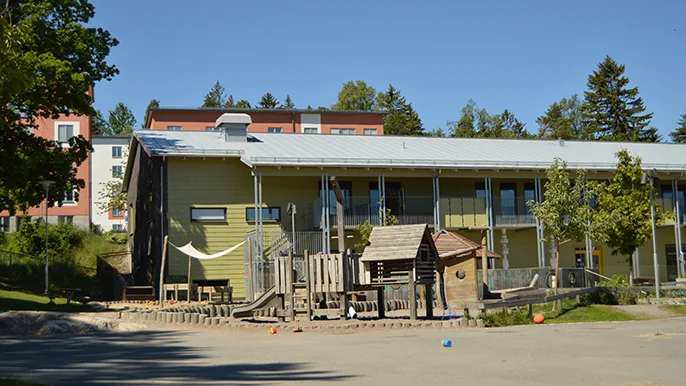 Ett ljusgrönt hus med en sandläda och en stor klätterställning utanför.