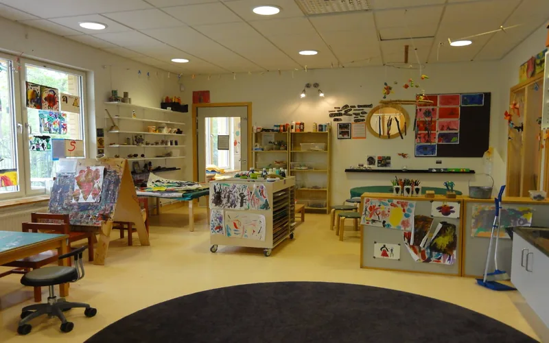 Kreativ inomhusmiljö med uppsatta teckningar, färg och pennor.