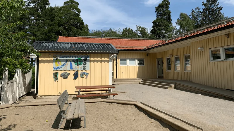 Ett gult enplanshus med en solig gård.