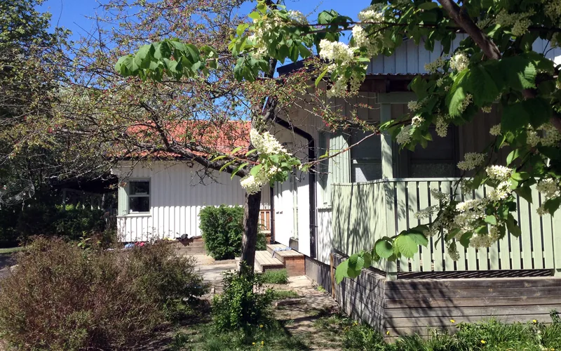 Vitt förskolehus med blommande träd utanför.