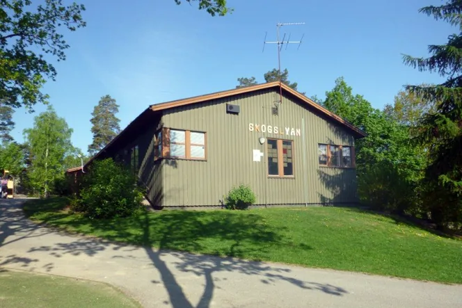 Ett grönt fristående hus på en kulle med en grästmatta framför huset