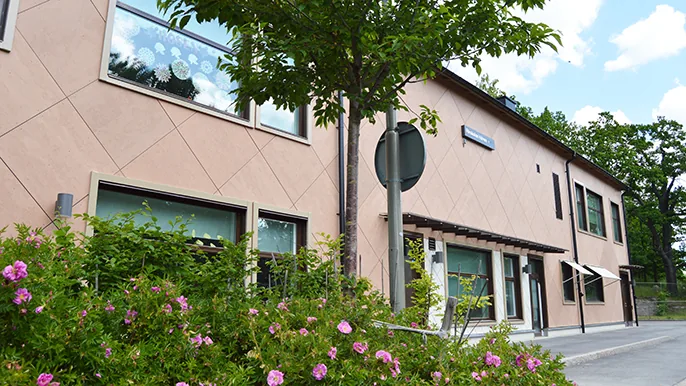 Bild av förskolan, ett ljust två våning hus med rosenbuskar framför huset