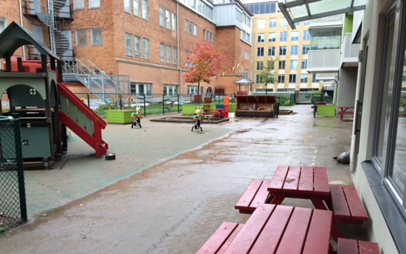 Förskolans utemiljö med lekytor, sandlådor med lekställning, rutschkana och gungdjur.