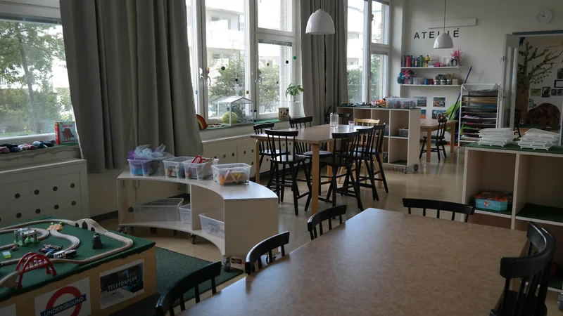 Lärmiljö med fönster ut mot gården med sittplatser, leksaker och andra lärmaterial.