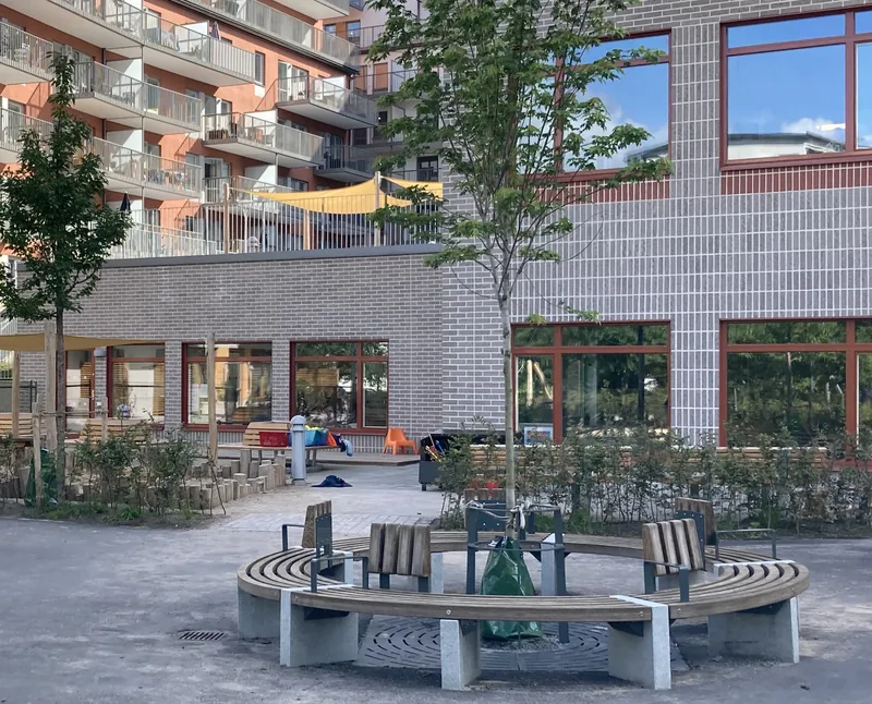 Gården med sittgrupp och lekredskap, förskolan i bakgrunden.