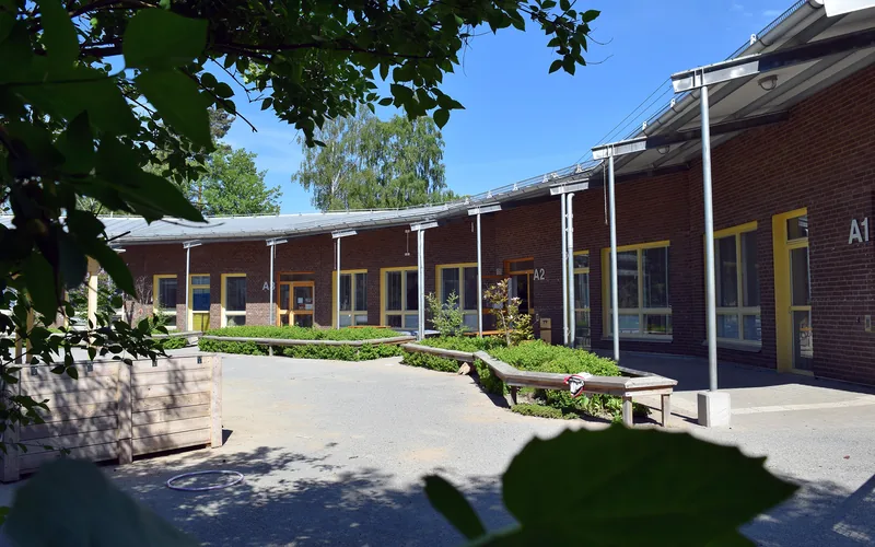 Förskolegården med det böjda förskolehuset i bakgrunden.